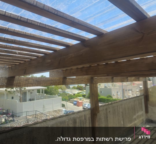 רשת מתוחה על פרגולה מעץ למניעת כניסת יונים